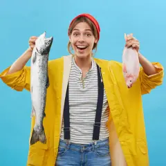Donna sorridente con un salmone e un pesce rosso, un'idea su come sostituire il pesce nella dieta.