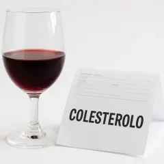 Un bicchiere di vino rosso accanto a un foglio con la scritta "COLESTEROLO".