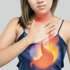 Donna con mano sul petto, evidenziato un bruciore allo stomaco e alla gola.