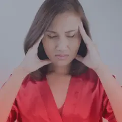 Donna con le mani sulle tempie, espressione sofferente, forse un sintomo di carenza di ferro al viso.