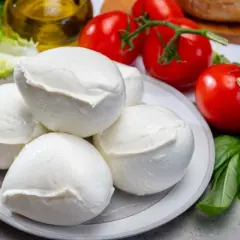 Mozzarella fresca su piatto, con pomodori, basilico e olio. Un piatto che, se mangiato in eccesso, potrebbe causare reflusso.
