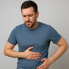 Uomo con espressione sofferente, mani sull'addome. Potrebbe indicare preoccupazione per un possibile **gamma gt alto tumore** o altri problemi epatici.