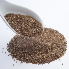 Un cucchiaio bianco versa semi di chia, piccoli alleati per sgonfiare la pancia.