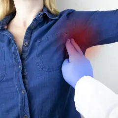 Medico esamina dolore sotto l'ascella sinistra, un sintomo che può essere associato a un infarto.