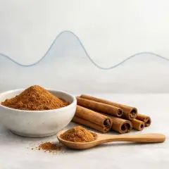 Cannella in polvere e bastoncini, con un cucchiaino. Uno sfondo con un grafico suggerisce un legame tra cannella e glicemia.