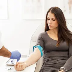 Donna in sala d'attesa per un prelievo di sangue. Il medico prepara l'ago per controllare la transaminasi GPT-ALT 57.