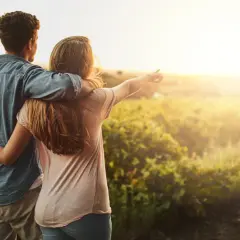 Coppia abbracciata al tramonto in un campo, un momento di serenità che ispira a capire come abbassare la pressione in modo naturale.