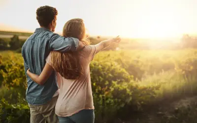 Coppia abbracciata al tramonto in un campo, un momento di serenità che ispira a capire come abbassare la pressione in modo naturale.