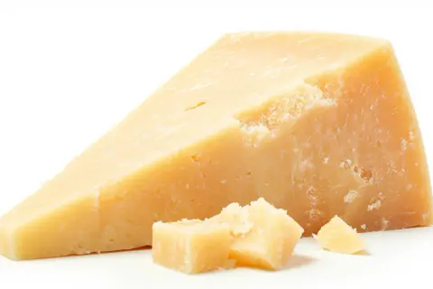 Un pezzo di Grana Padano, con scaglie sparse. Un alimento gustoso, ma attenzione al colesterolo.