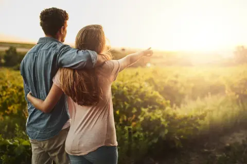 Coppia abbracciata al tramonto in un campo, un momento di serenità che ispira a capire come abbassare la pressione in modo naturale.