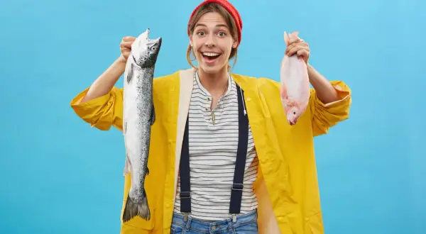 Donna sorridente con un salmone e un pesce rosso, un'idea su come sostituire il pesce nella dieta.