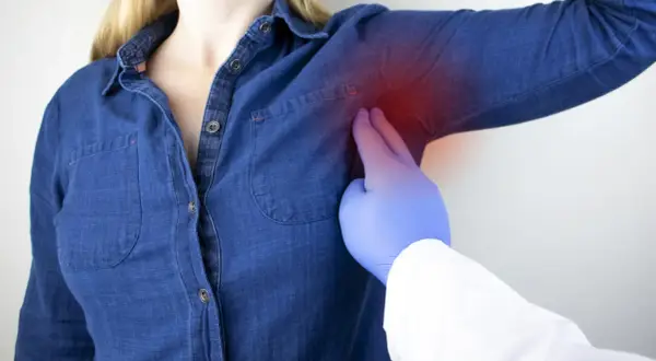 Medico esamina dolore sotto l'ascella sinistra, un sintomo che può essere associato a un infarto.