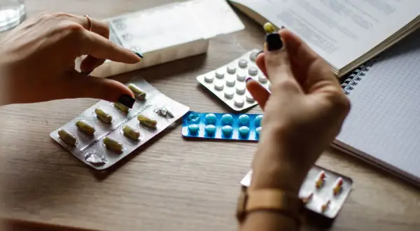 Mani con pillole e blister, cercando alternative cosa prendere al posto delle statine.