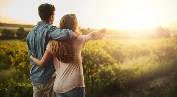 Coppia abbracciata al tramonto in un campo, un momento di serenità che ispira a capire come abbassare la pressione in modo naturale.