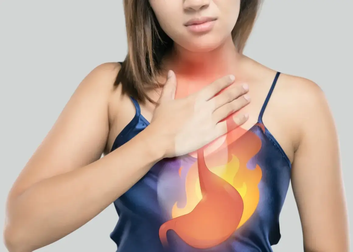 Donna con mano sul petto, evidenziato un bruciore allo stomaco e alla gola.