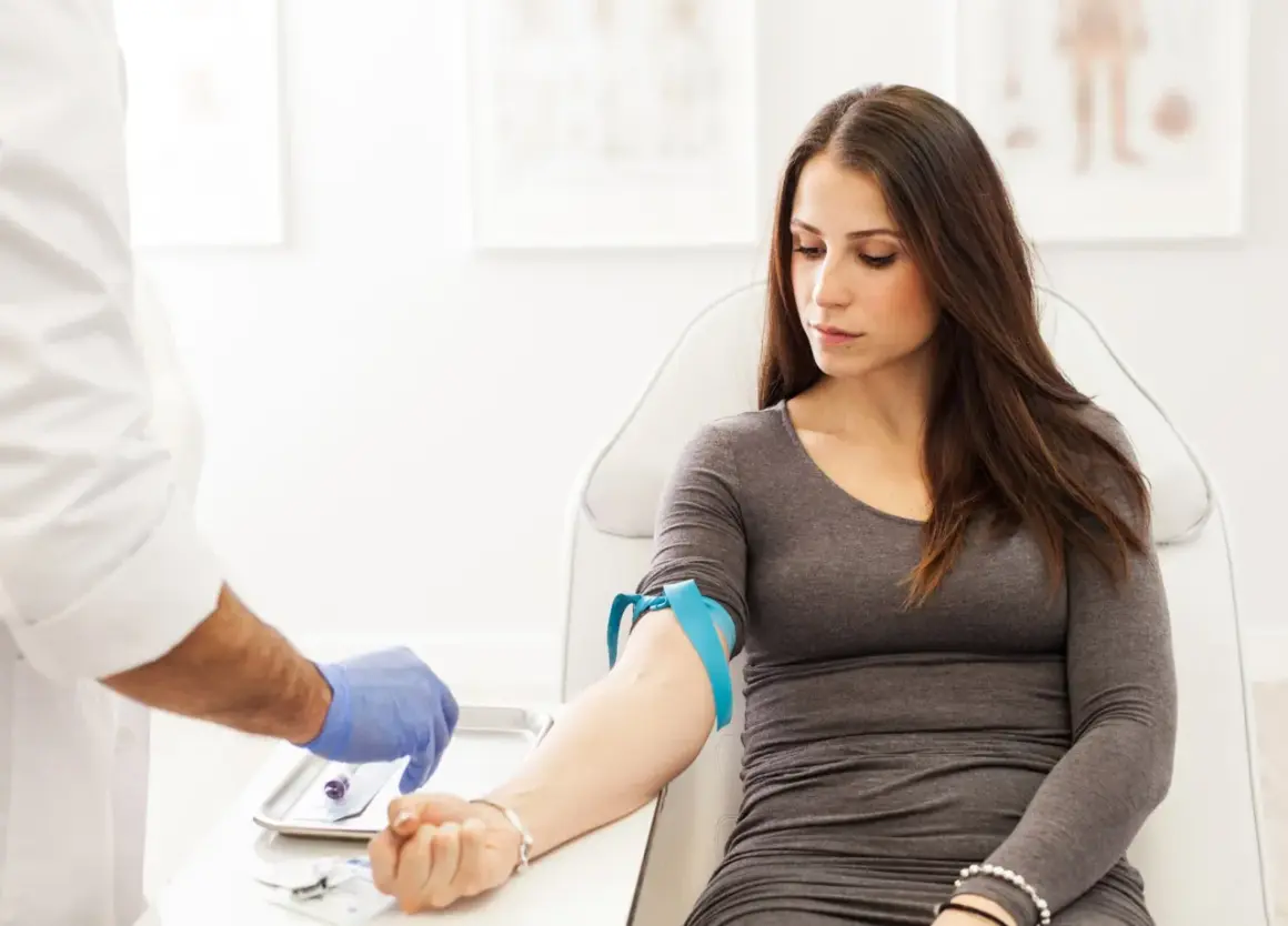 Donna in sala d'attesa per un prelievo di sangue. Il medico prepara l'ago per controllare la transaminasi GPT-ALT 57.