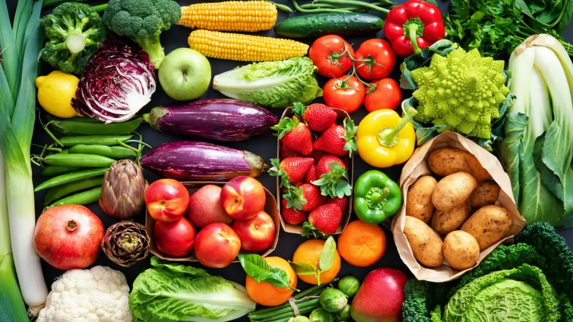 Varietà di verdure fresche e frutta, ideale per una tabella verdure per diabetici: broccoli, pomodori, peperoni, melanzane, fragole, patate, mele, arance, cavoli e altro.