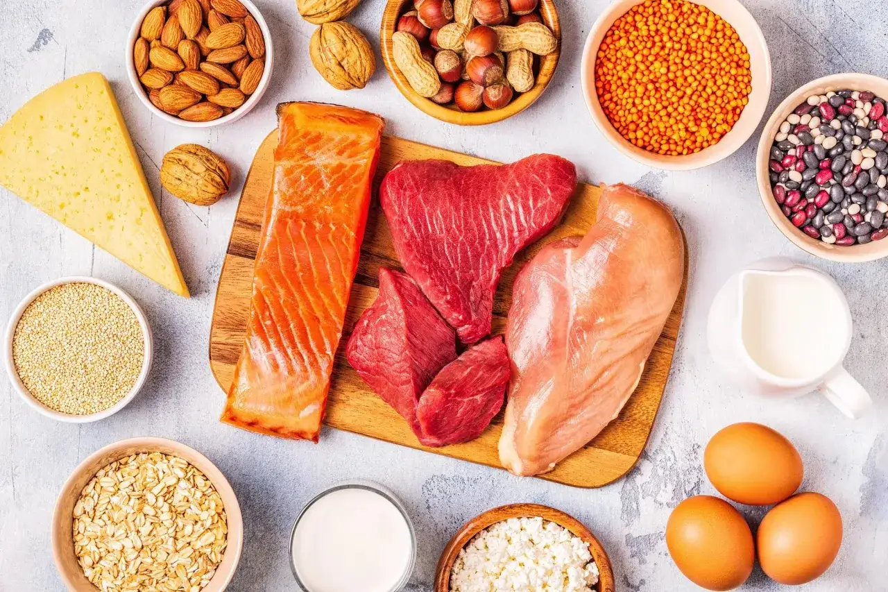 Variet&agrave; di alimenti ricchi di proteine: salmone, carne, pollo, uova, formaggio, latte, legumi, frutta secca e cereali.