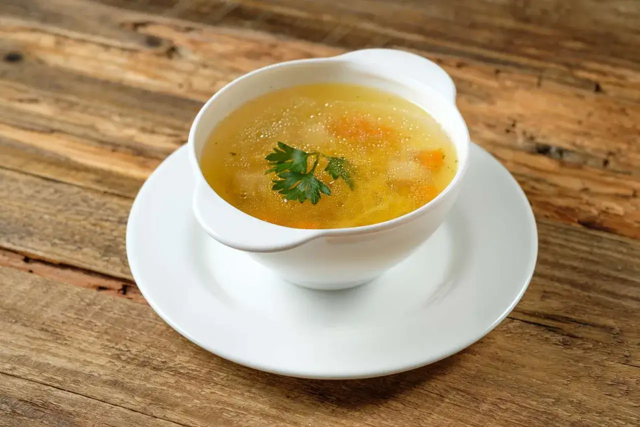 Brodo caldo con carote e prezzemolo, un classico per sapere cosa mangiare con la febbre.