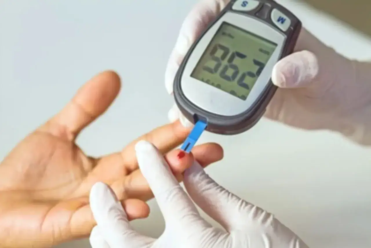Misurazione della glicemia a digiuno: un dito viene punto per ottenere una goccia di sangue, inserita in un glucometro che mostra 96.