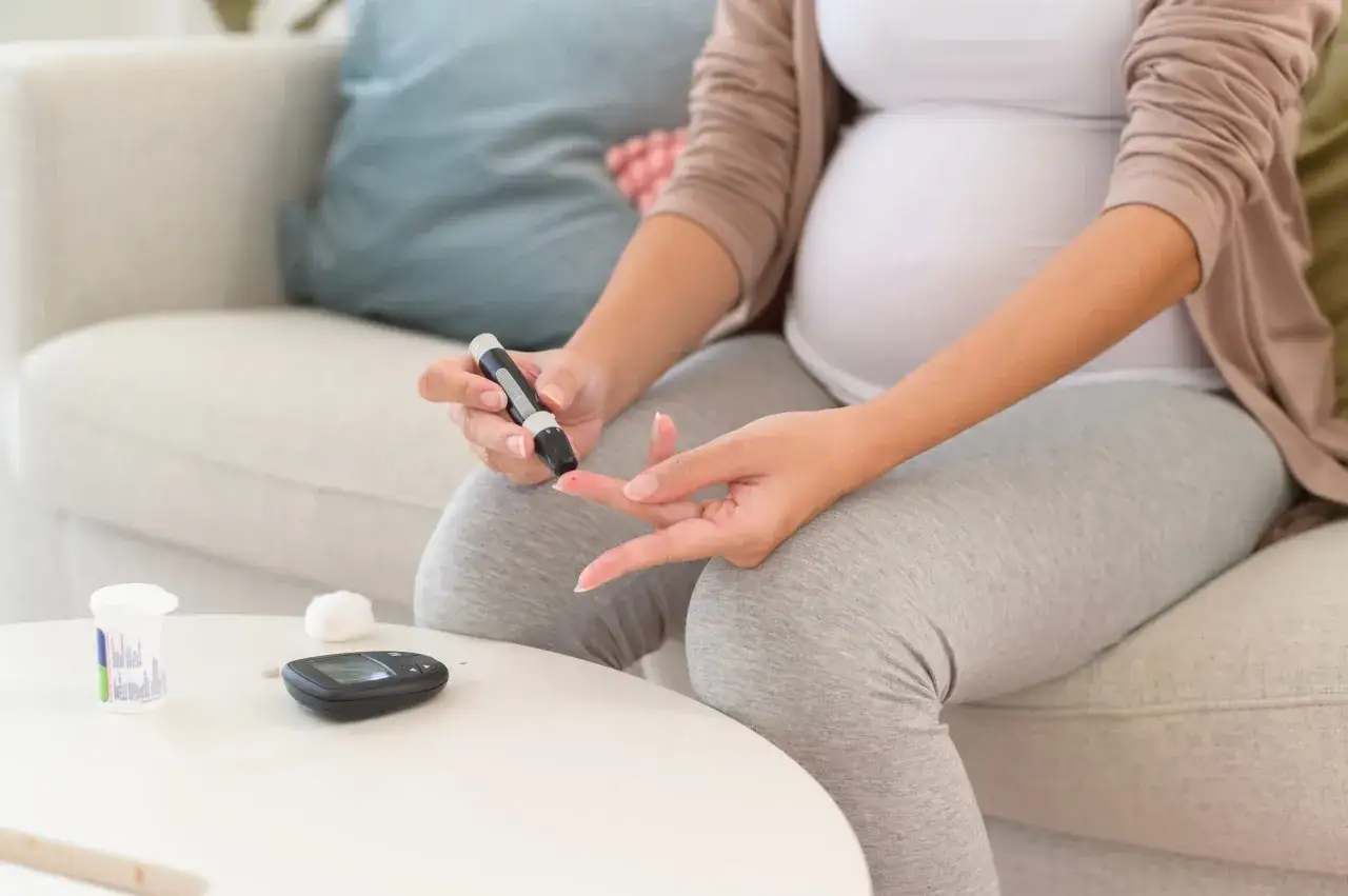 Donna incinta controlla la glicemia con un glucometro, preoccupata per la glicemia alta in gravidanza.