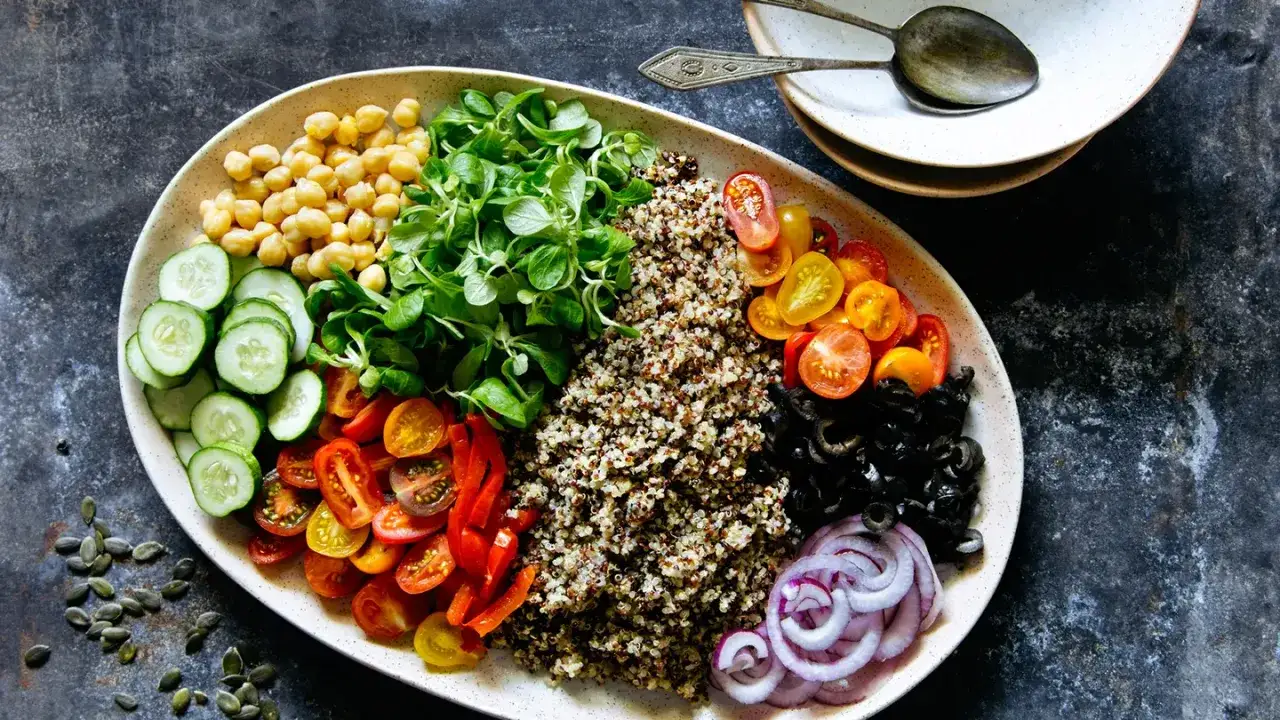 Piatto colorato con ceci, verdure fresche, pomodorini, olive e cipolla rossa, ideale per una dieta per glicemia alta e colesterolo.