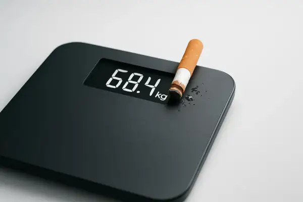 Bilancia digitale mostra 68.4 kg con una sigaretta. Forse qualcuno pensa che fumare fa dimagrire, ma è un mito pericoloso.