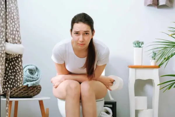 Donna sul water con espressione preoccupata, pensando a cosa mangiare per il fecaloma.